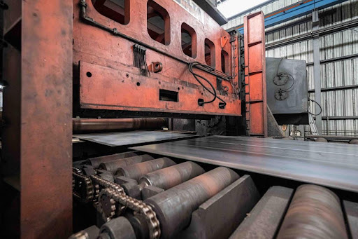 Industrial machine processing steel sheets in a manufacturing plant.