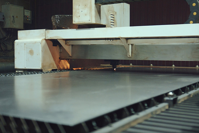 Industrial CNC laser cutting machine processing a large metal sheet.
